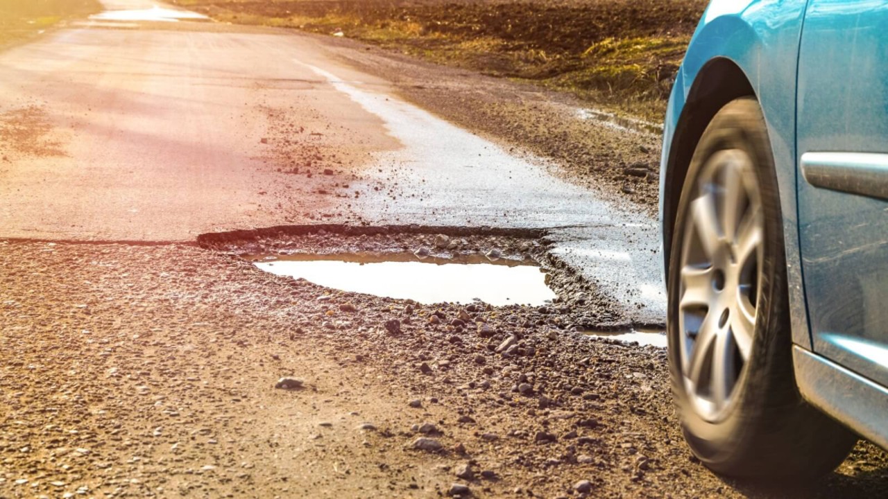 Dziura w drodze jezdni i uszkodzone auto